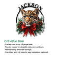 Leopard Christmas metal sign with a bold big cat portrait, evergreen wreath accents, pinecones, and a festive red bow