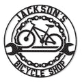 Round cyclist metal sign featuring a bicycle silhouette, crossed wrenches, chain accents, and bold bike shop styling