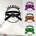 Karate belt metal sign displayed on a wall with black, purple, brown, and green belt color examples