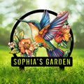 Colorful hummingbird metal garden sign surrounded by vibrant flowers and leafy botanical accents