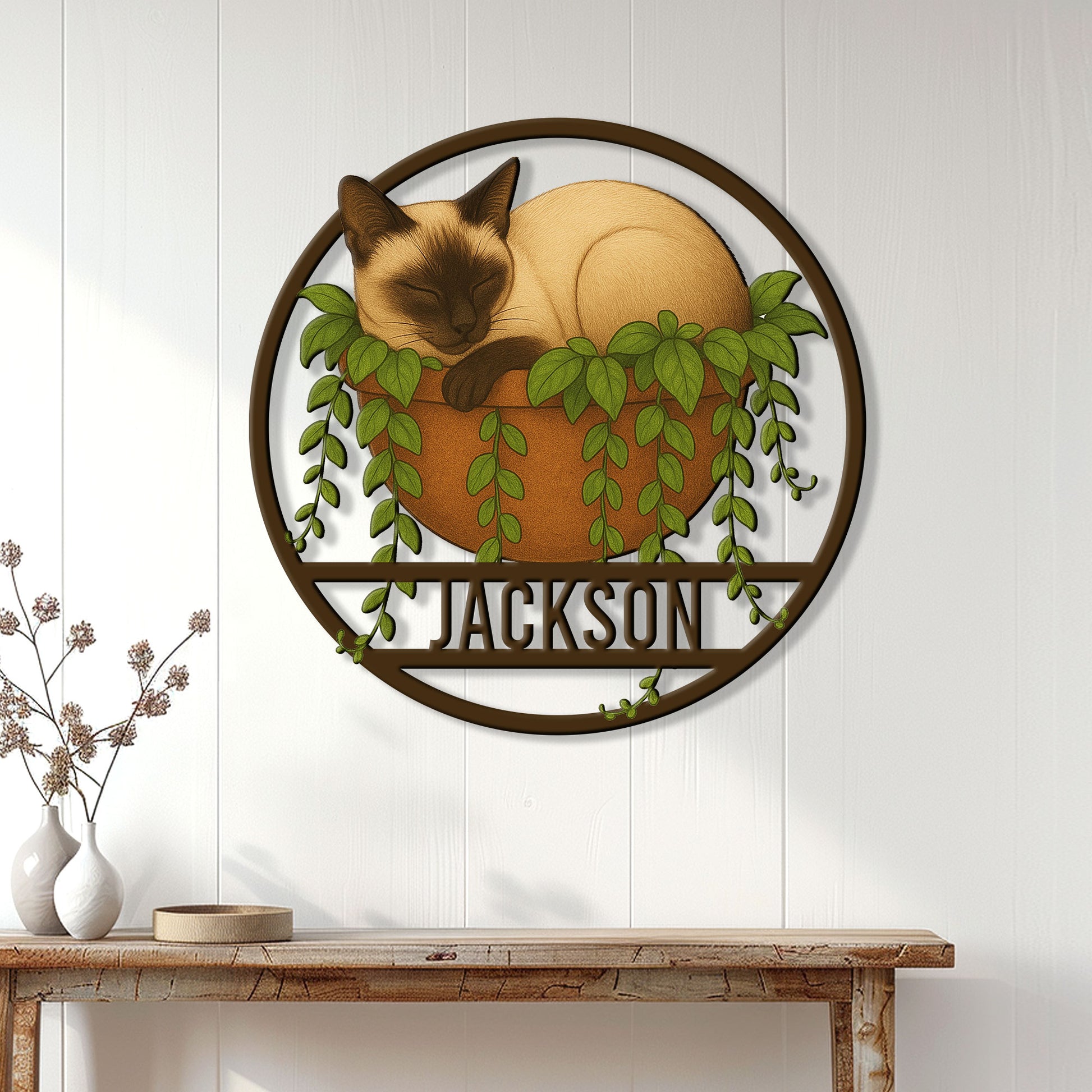 Siamese cat wall sign displayed on a light wood-paneled wall above a console table