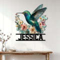 Hummingbird wall sign displayed on a light paneled wall above a console table with floral home decor
