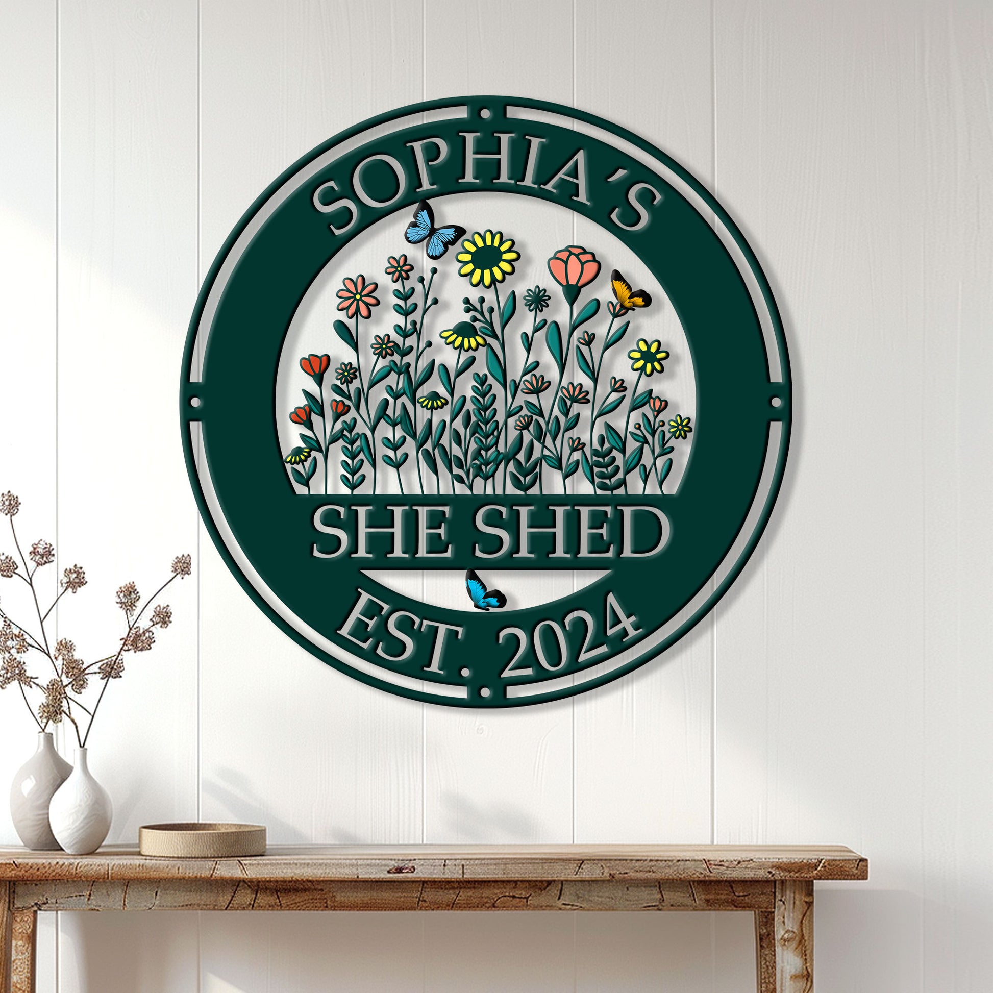 Floral She Shed metal sign displayed on a white paneled wall above a rustic wooden console