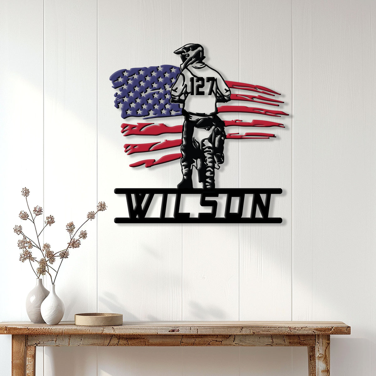 Patriotic motocross rider metal wall sign displayed above a console table in a bright home interior