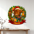 Festive Highland cow wall sign displayed on a white paneled wall above a wooden console table
