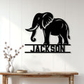 Black elephant silhouette sign displayed on a white paneled wall above a rustic console table