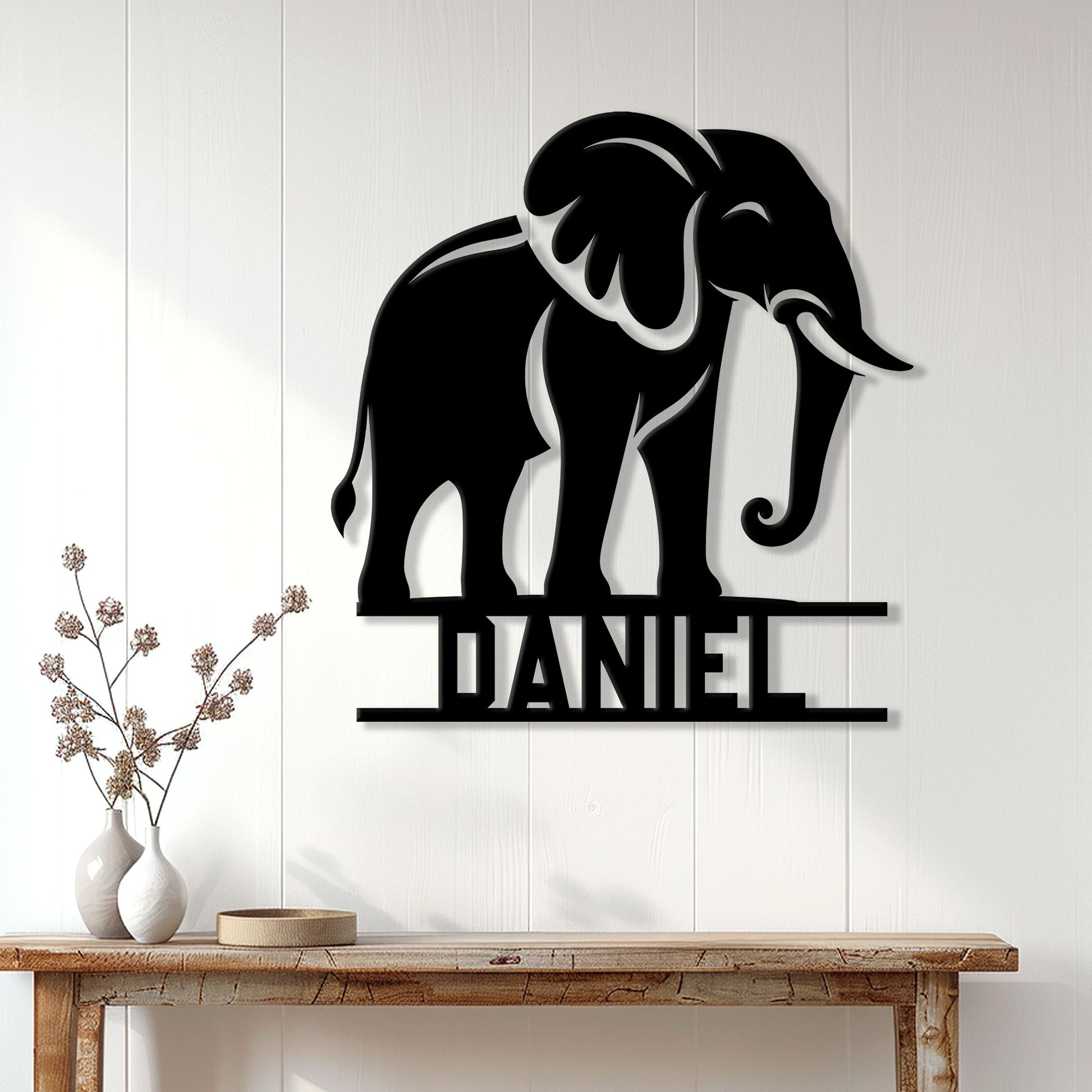 Black elephant metal wall sign displayed on a bright paneled wall above a console table