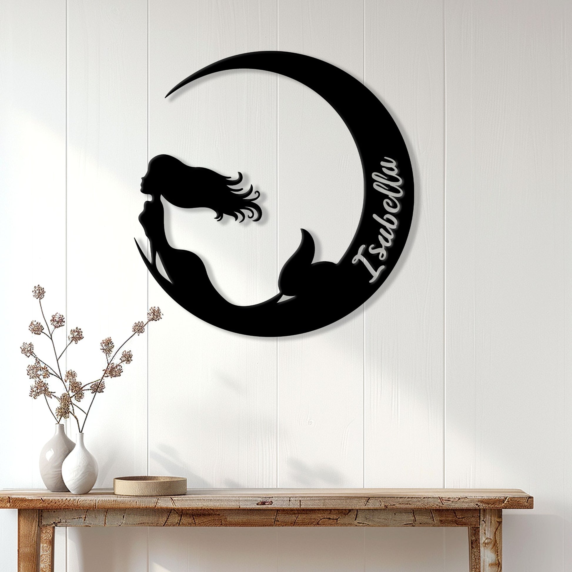 Black mermaid metal wall sign displayed on a white paneled wall above a console table