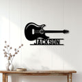 Black electric guitar wall sign displayed above a console table in a bright home interior