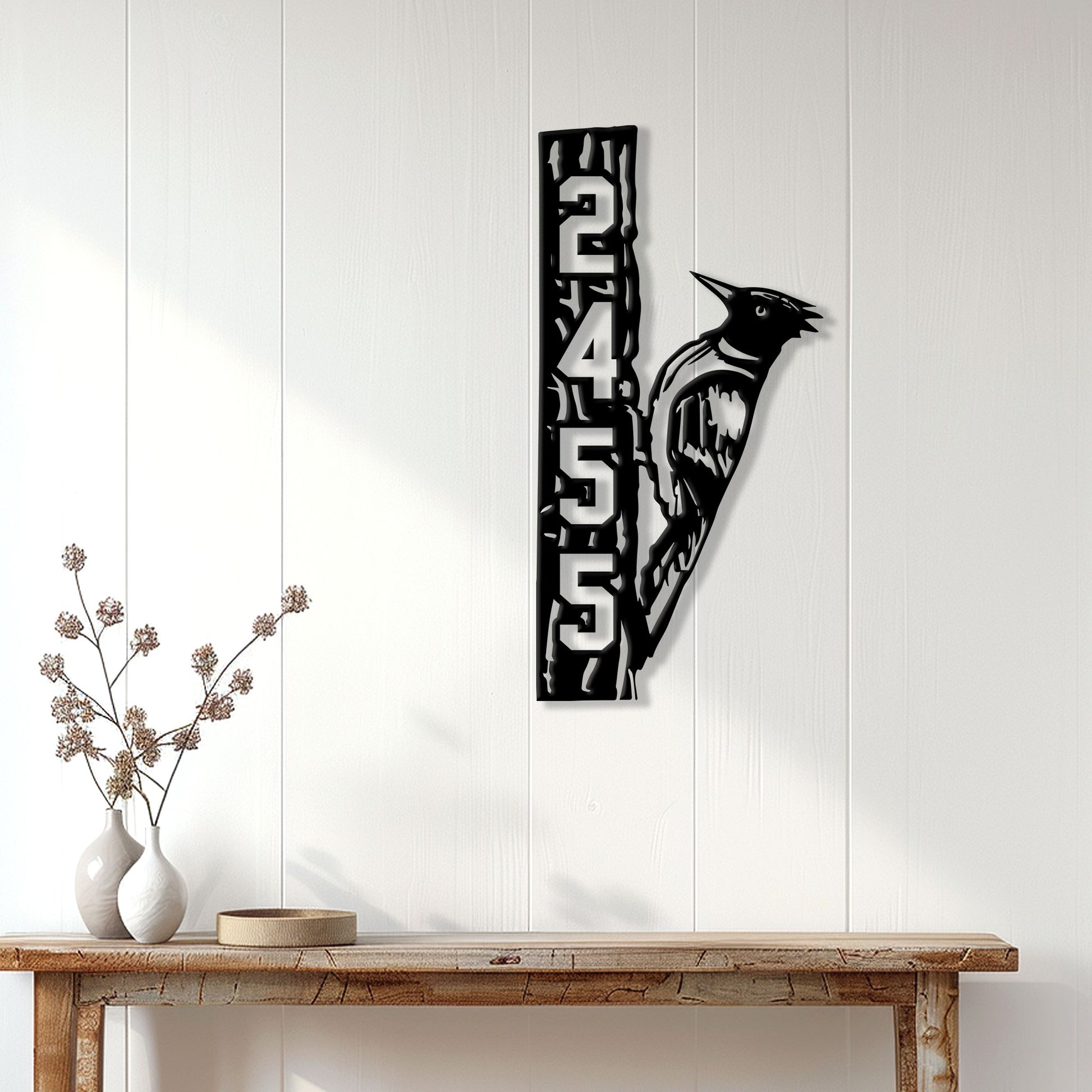 Woodpecker metal wall sign displayed on a white paneled wall above a wooden console table