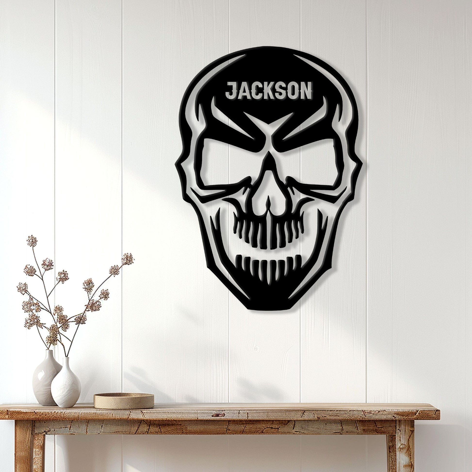 Black and white skull metal wall sign displayed on a white paneled wall above a console table