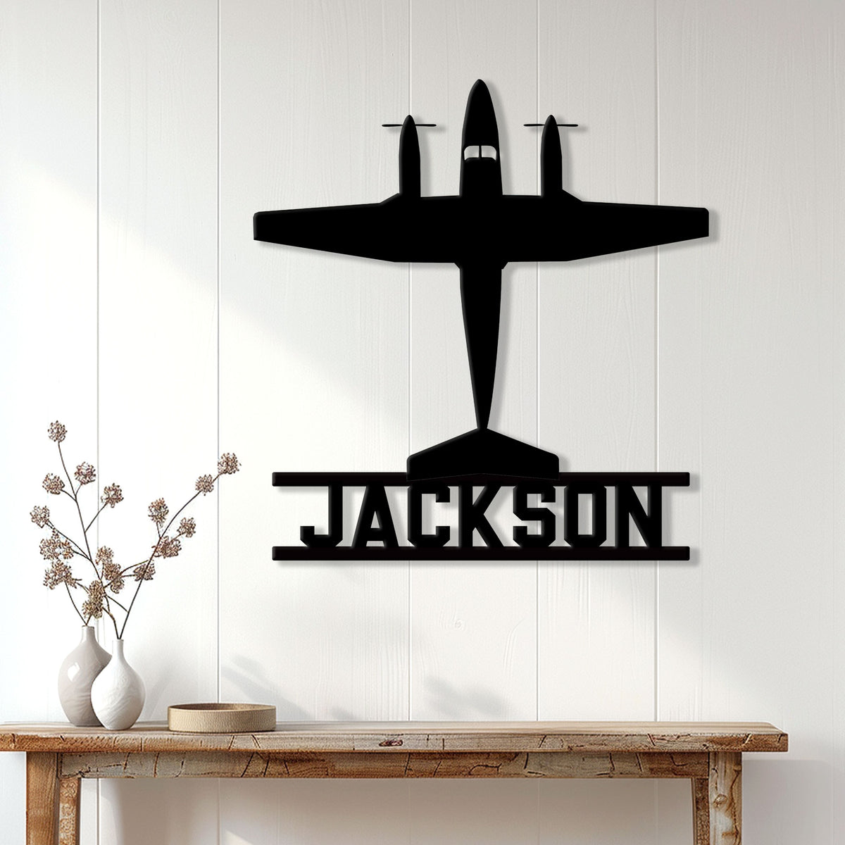 Black airplane pilot metal sign displayed on a bright paneled wall above a console table