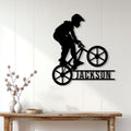 Black BMX rider silhouette metal sign displayed on a light wood-paneled wall