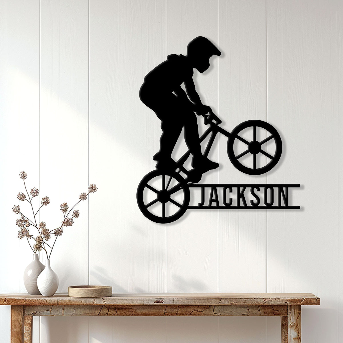 Black BMX rider silhouette metal sign displayed on a light wood-paneled wall