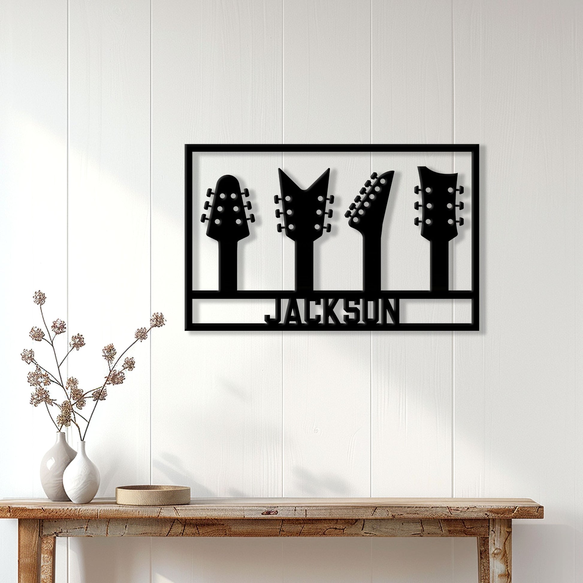 Black guitar headstock metal sign displayed on a white paneled wall above a wood console table