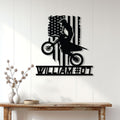 Black motocross rider metal wall sign displayed on a white paneled wall in a home