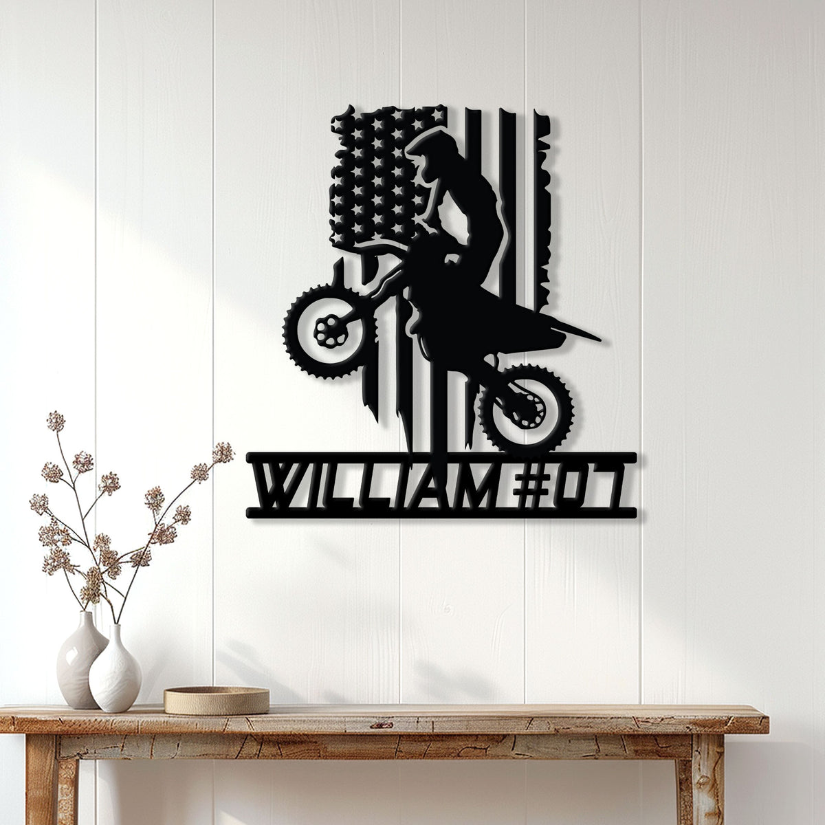 Black motocross rider metal wall sign displayed on a white paneled wall in a home