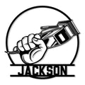 Black and white barber metal sign featuring a hand gripping hair clippers inside a bold circular frame