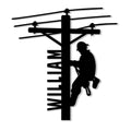 Black silhouette metal sign showing a lineman climbing a utility pole beneath multiple power lines