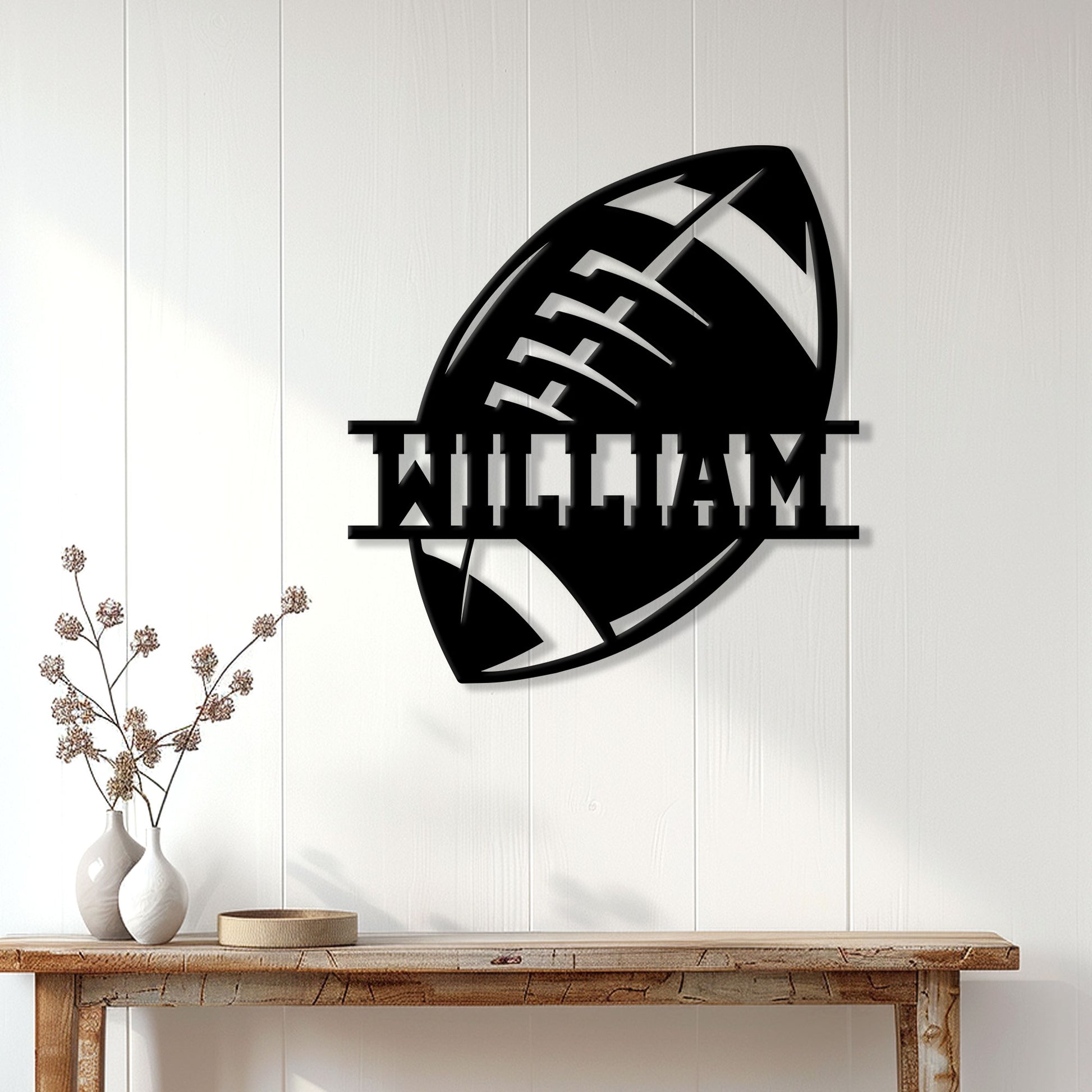 Black football wall sign displayed on white wood paneling above a rustic console table