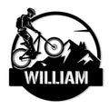 Mountain biker metal sign featuring a rider climbing past bold mountain peaks and pine trees