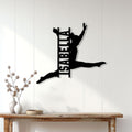 Black gymnastics wall sign displayed on a bright paneled wall above a rustic console table