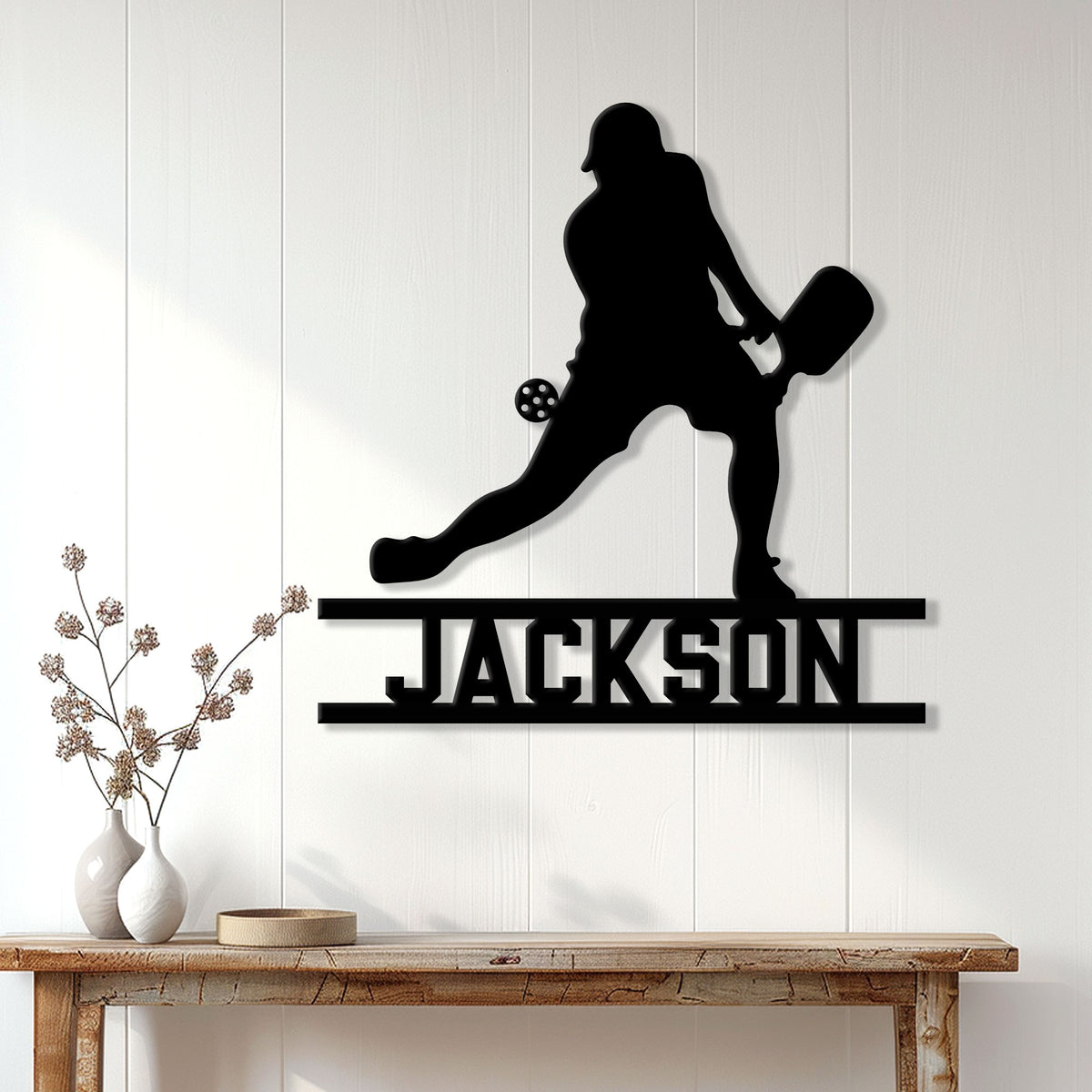 Pickleball metal wall sign displayed on a bright paneled wall above a console table