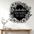 Floral She Shed wall sign displayed on a light wood-paneled interior wall