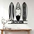 Surfing metal sign displayed on a light wood wall above a console table in a coastal home setting