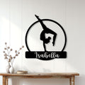 Gymnast silhouette metal sign displayed on a light wood-paneled wall above a console table