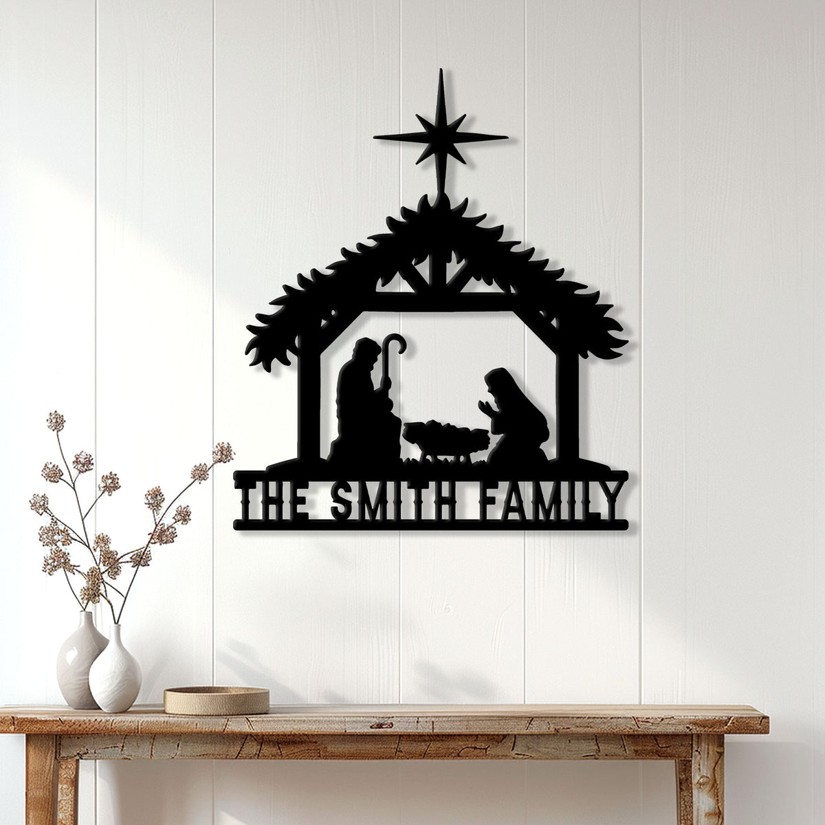 Black nativity Christmas metal sign displayed on a white paneled wall above a wooden console table