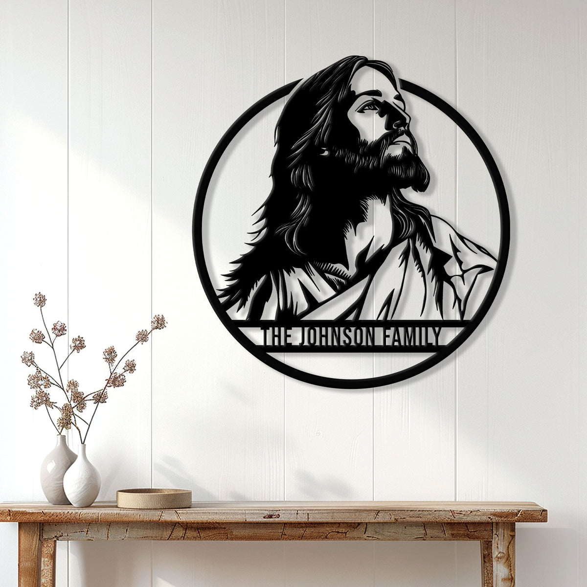 Jesus family metal sign displayed on a light wood-paneled wall above a console table
