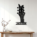 Black guitar headstock metal wall sign displayed on a bright paneled wall