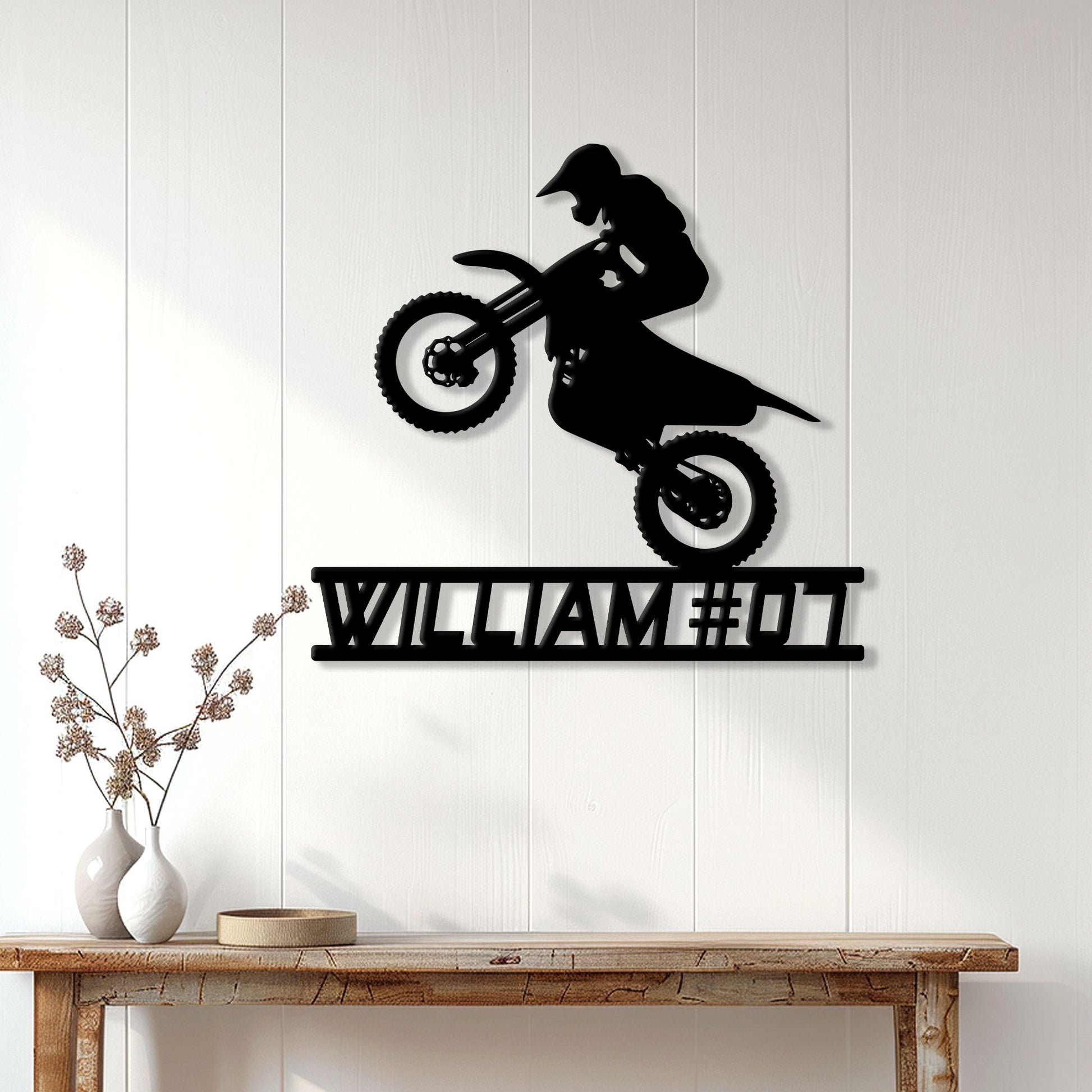 Black motocross rider metal wall sign displayed on white paneled home decor wall