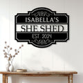 Elegant She Shed metal sign displayed on a white paneled wall above a wood console table