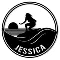 Round surfing metal sign featuring a female surfer silhouette riding a curling wave at sunset
