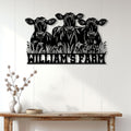 Three-cow metal farm sign displayed on a light farmhouse wall above a rustic console table