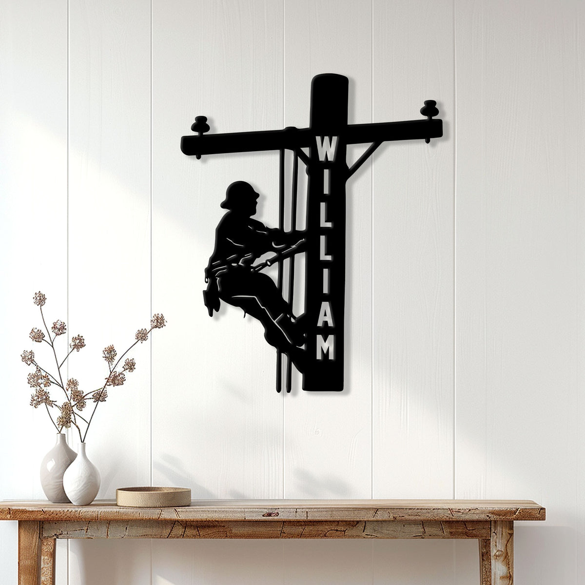 Black lineman metal wall sign displayed on a bright paneled wall above a console table