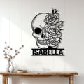 Black skull and rose metal wall sign displayed on a light wood-paneled wall above a console table