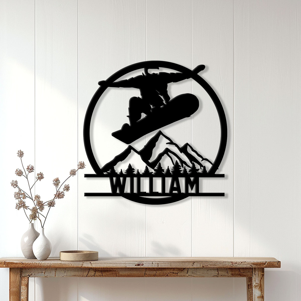 Black snowboarding wall sign displayed on a light wood-paneled wall above a console table