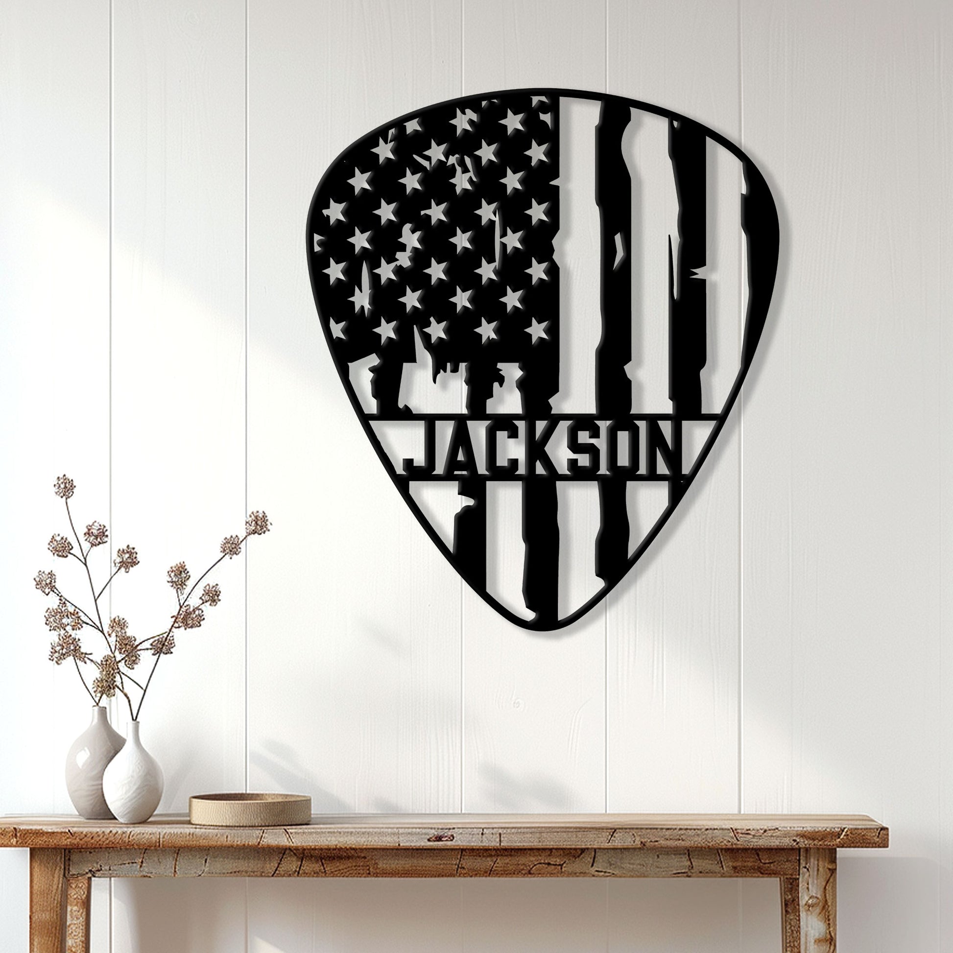 Patriotic guitar pick wall sign displayed on a white paneled wall above a console table