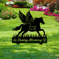 Winged horse remembrance sign shown among flowers and lawn landscaping
