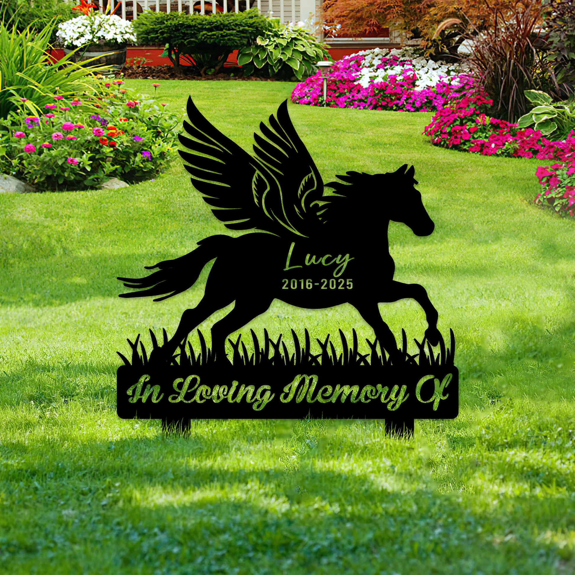 Winged horse remembrance sign shown among flowers and lawn landscaping