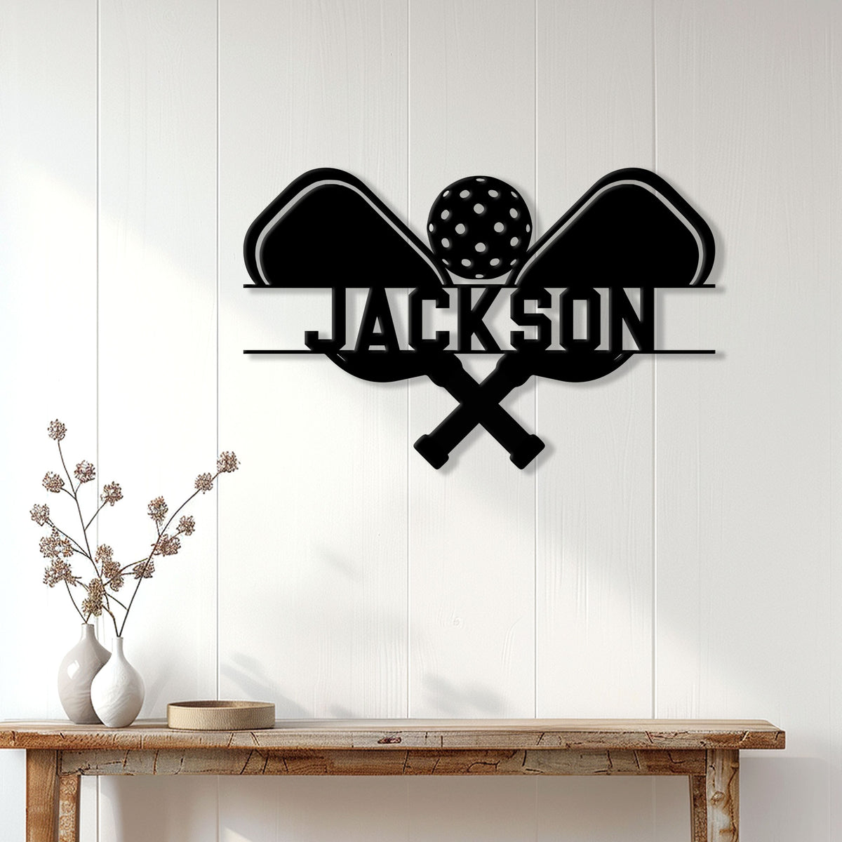Pickleball wall sign displayed on a white paneled wall above a wood console table