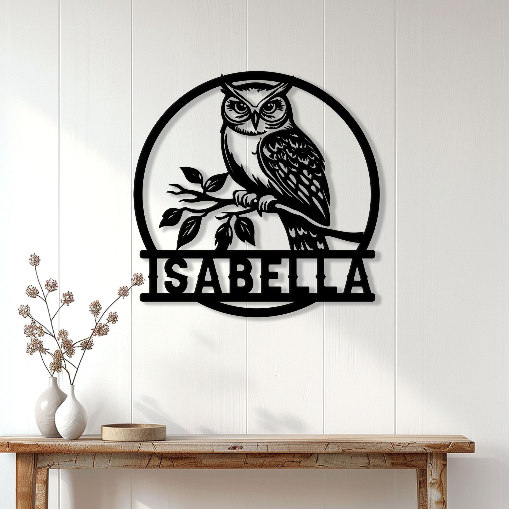 Black owl wall sign displayed on a white paneled wall above a rustic console table