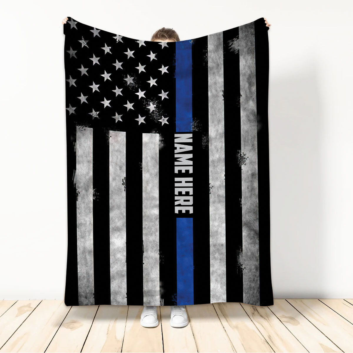 Person holding a police throw blanket featuring distressed stars, stripes, and thin blue line artwork