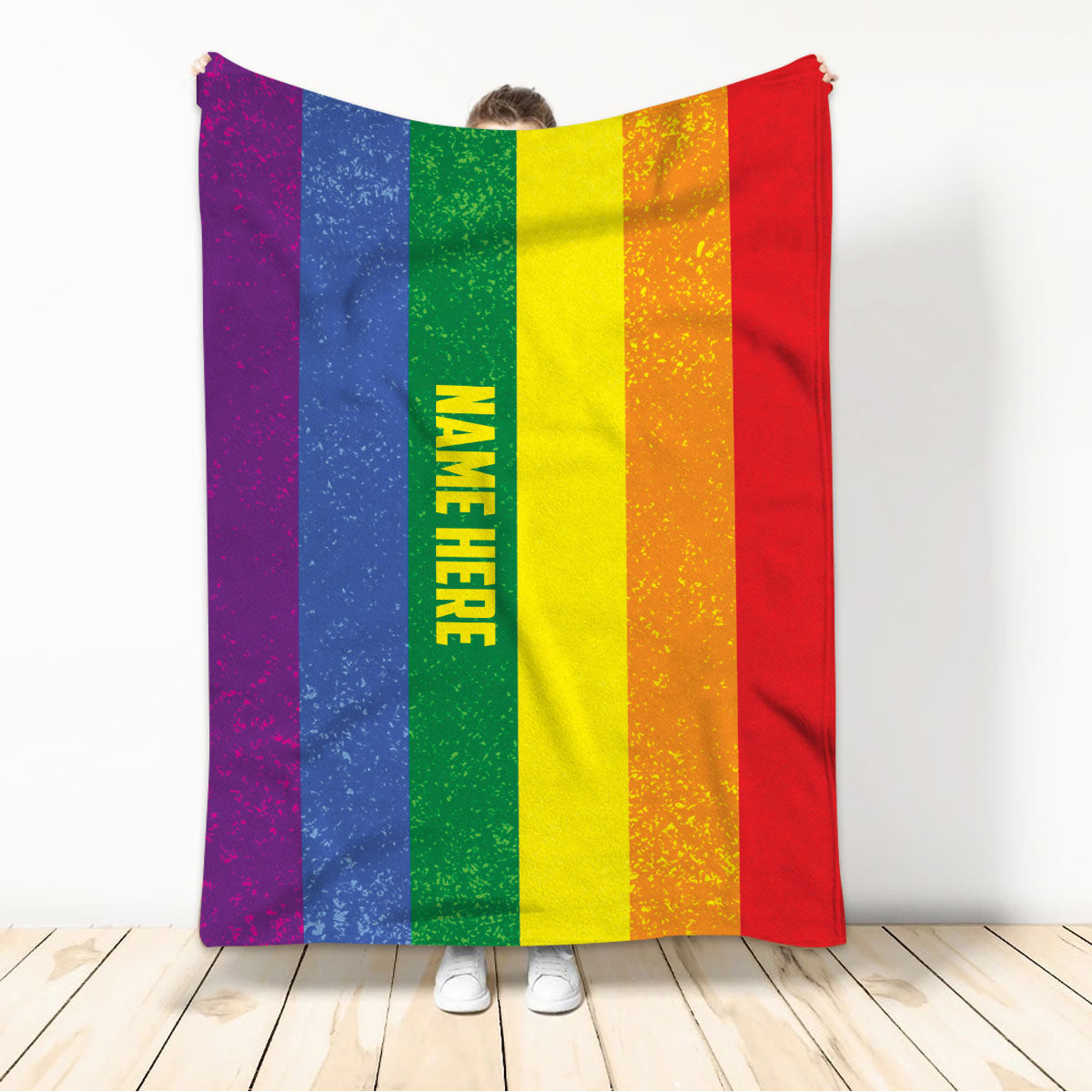 Person holding a colorful LGBT Pride rainbow throw blanket with bold striped artwork