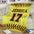 Softball throw blanket with bold yellow and burgundy ball-stitch artwork displayed on a living room sofa