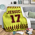 Custom softball throw blanket shown on a gray couch with bold sports artwork and ball-stitch borders