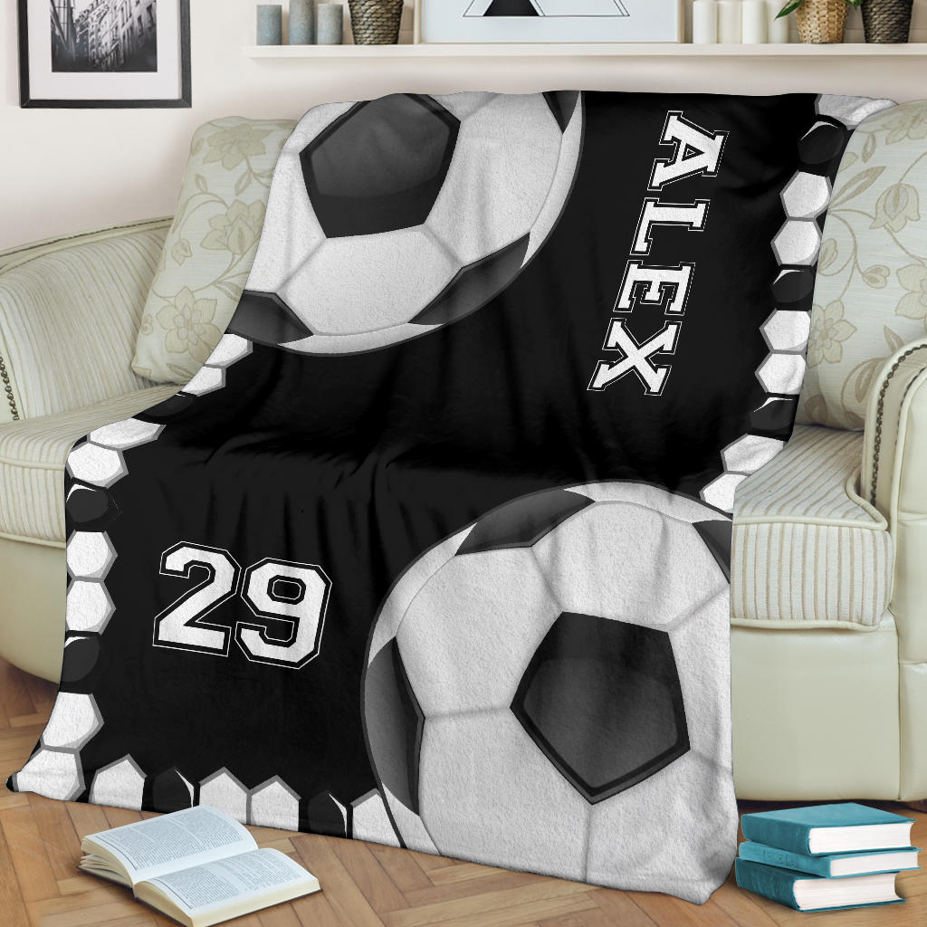 Black and white soccer throw blanket draped over an armchair with bold ball artwork